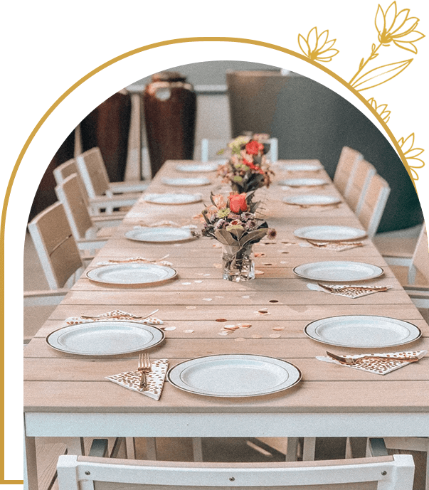 A long table with white plates and flowers on it.