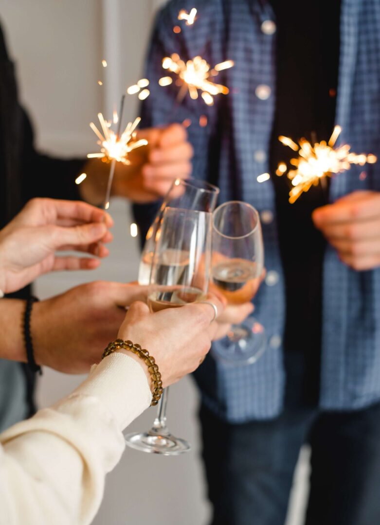 A group of people holding glasses with wine and sparklers.