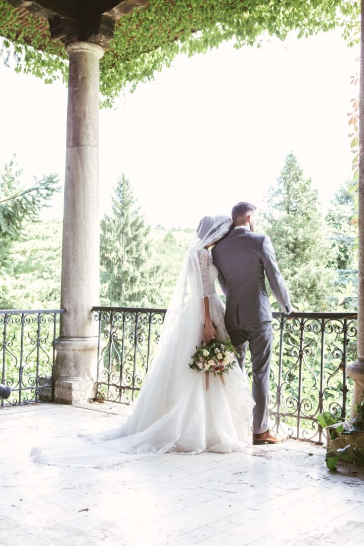 A bride and groom standing on the balcony of their wedding venue.