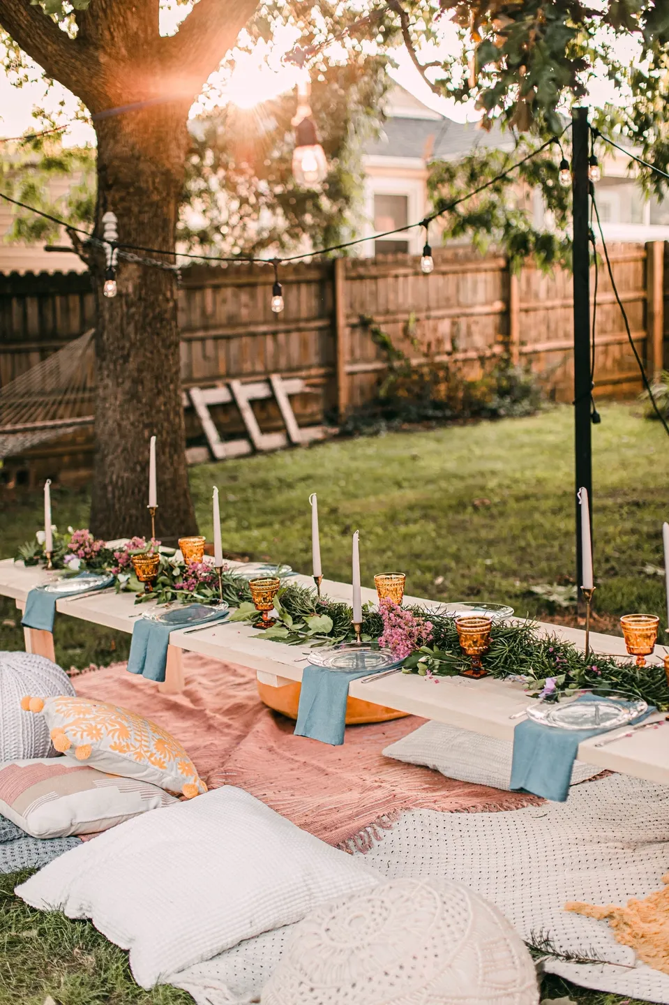 A backyard with flowers and candles on the ground.