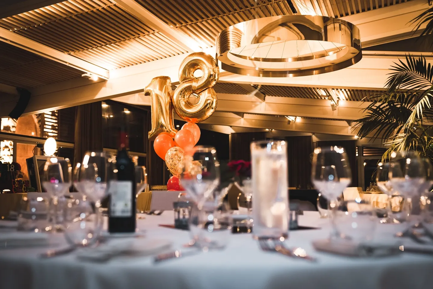 A table with wine glasses and balloons on it.